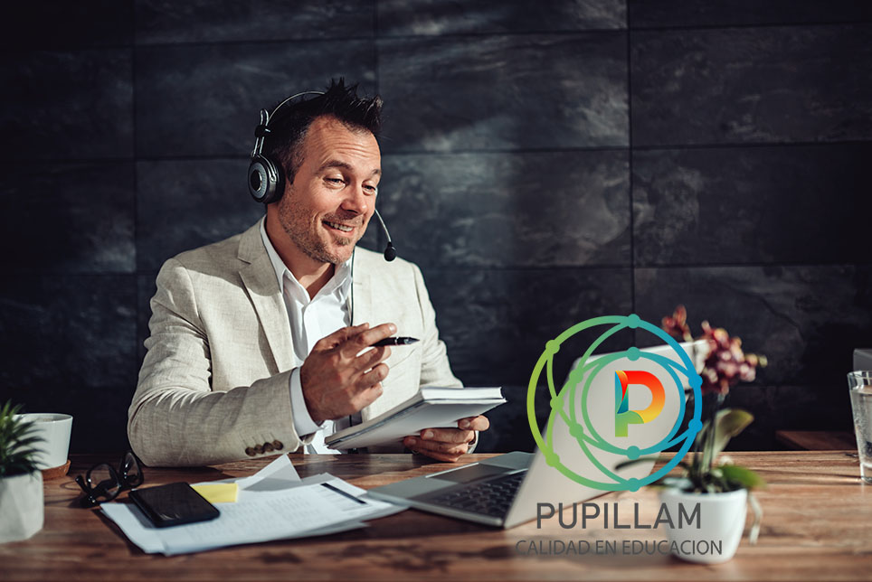Businessman wearing linen suit sitting at his desk by the window and having online meeting in his office